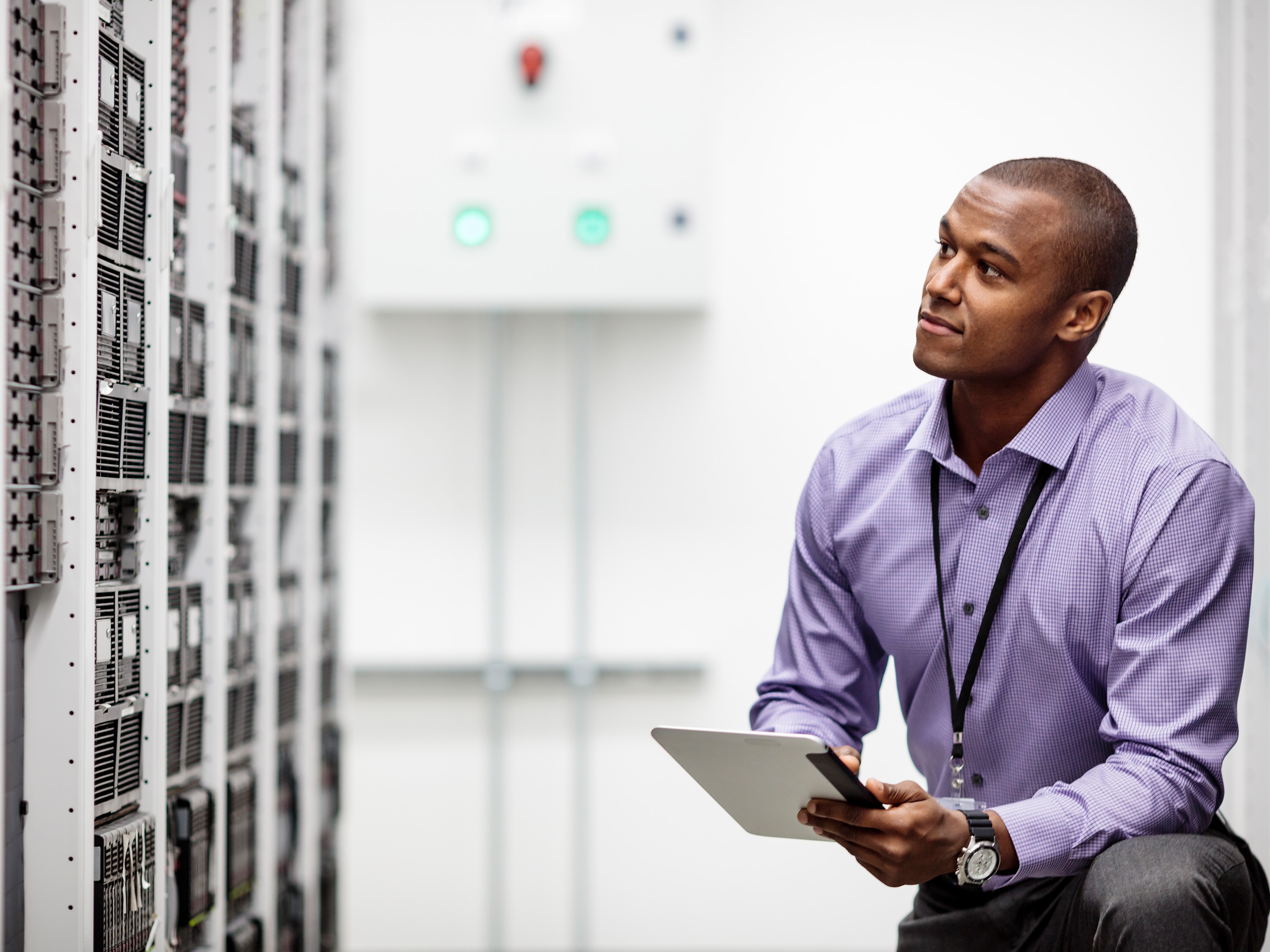 Engineer using digital tablet examining cabinets in high tech server room.