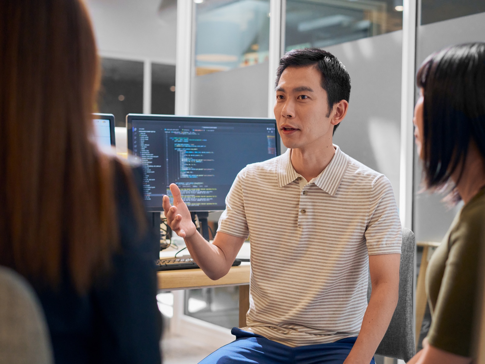 Portrait of a male software developer writing code, talking to his colleagues.