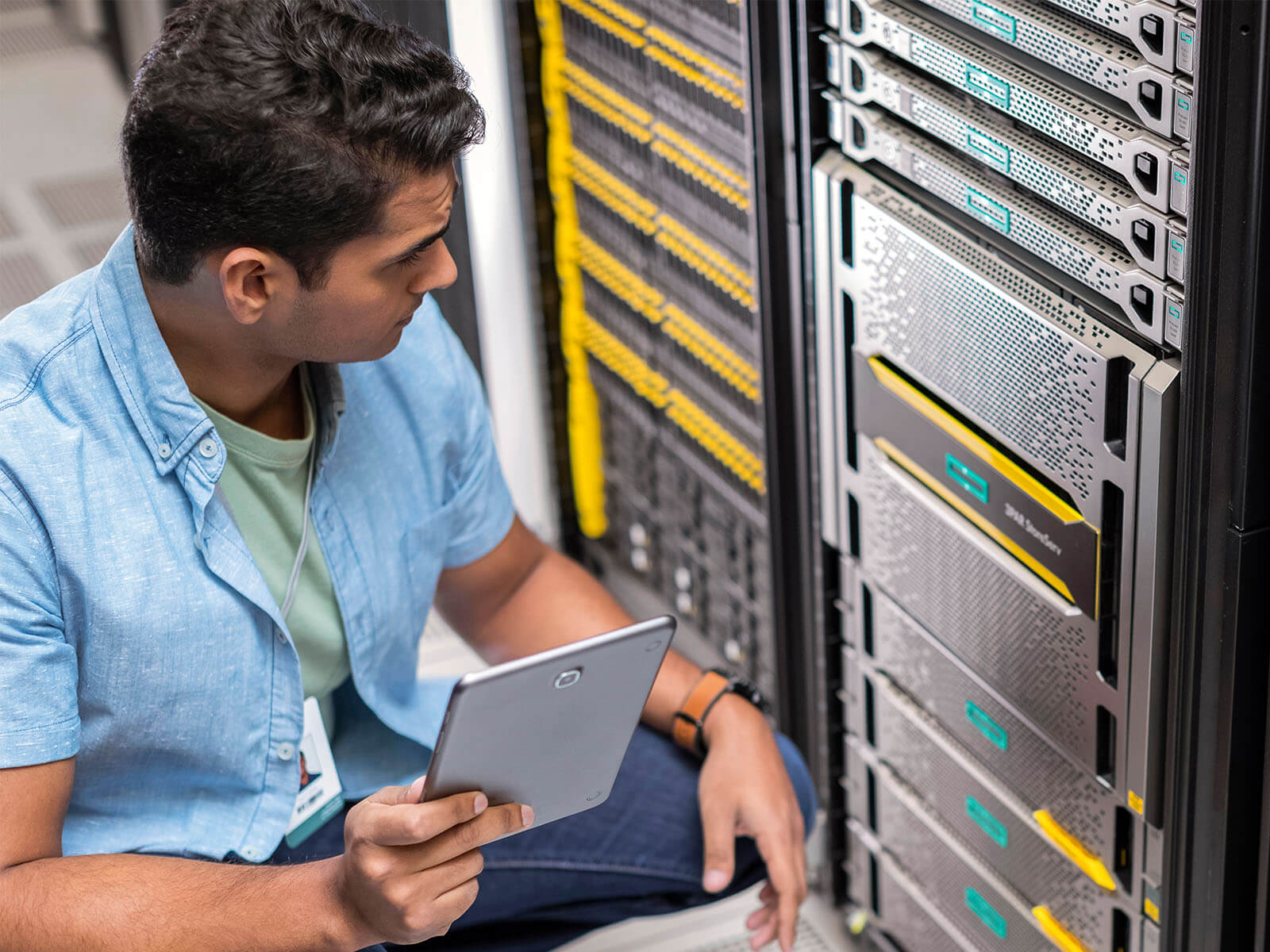 Man with tablet reviewing a rack in a server room.