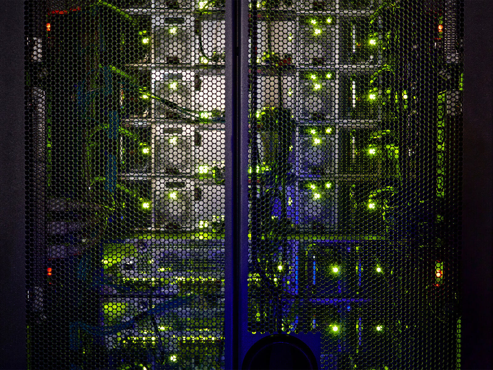 Close up of cables and wires plugging into glowing mainframe infrastructure of computer server in cabinet.