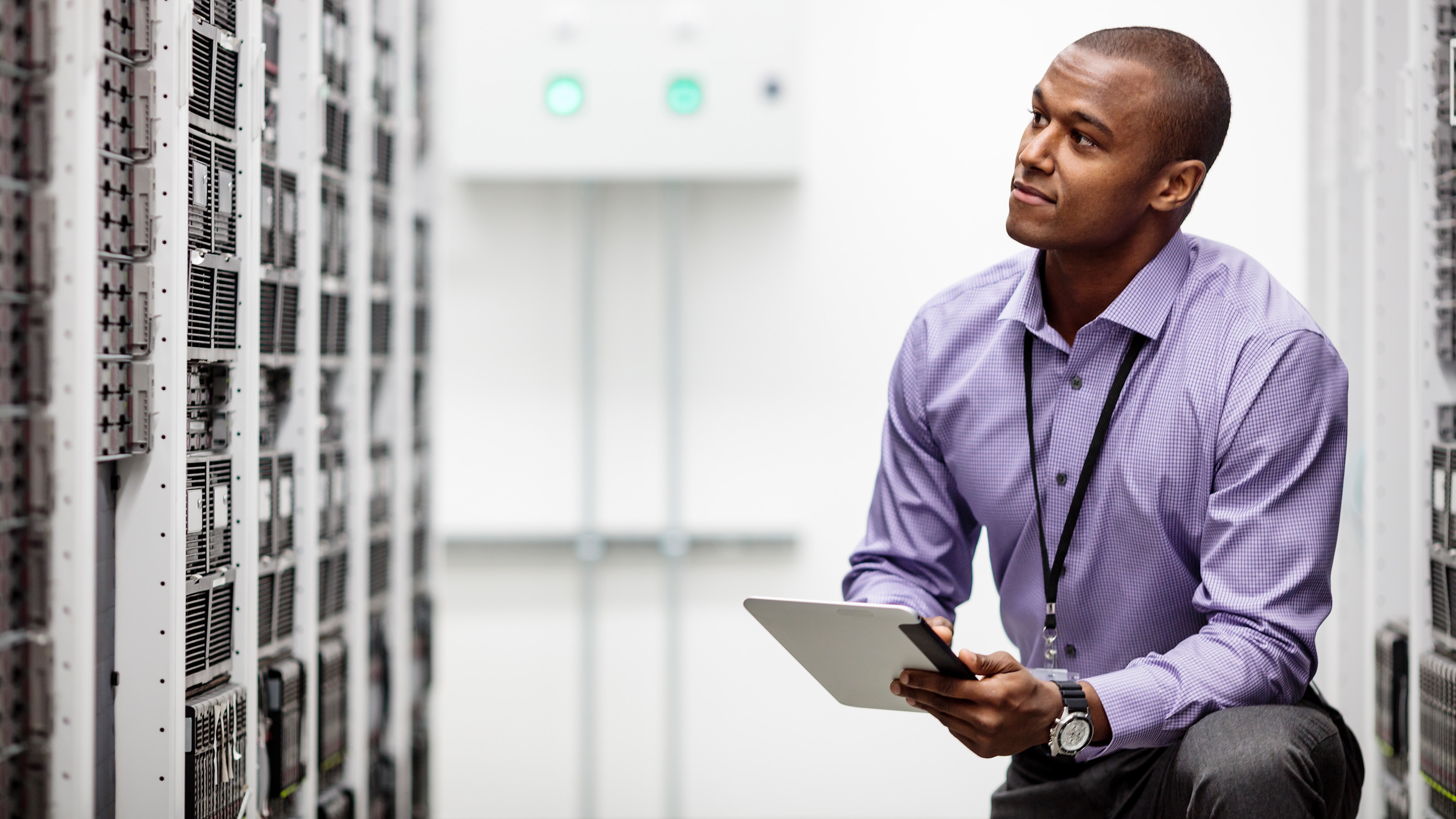 Engineer using digital tablet examining cabinets in high tech server room.