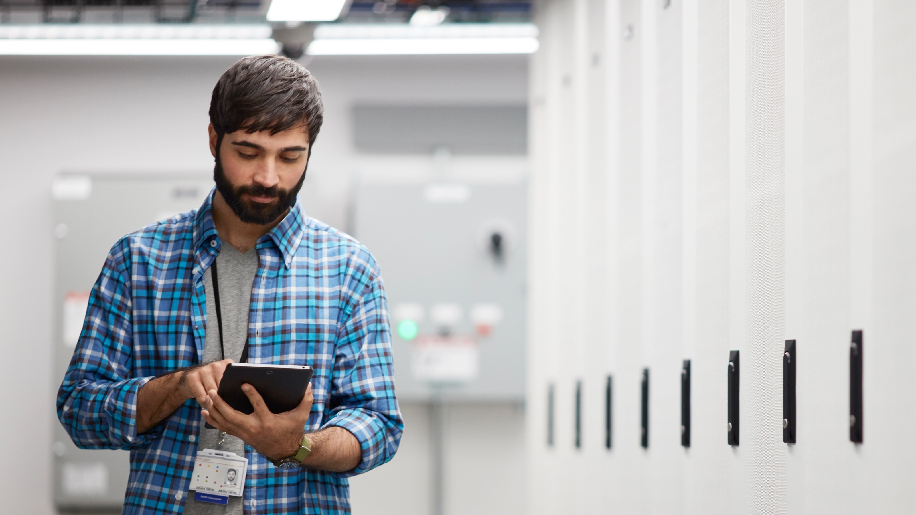 Engineer using digital tablet and walking in high tech server room.