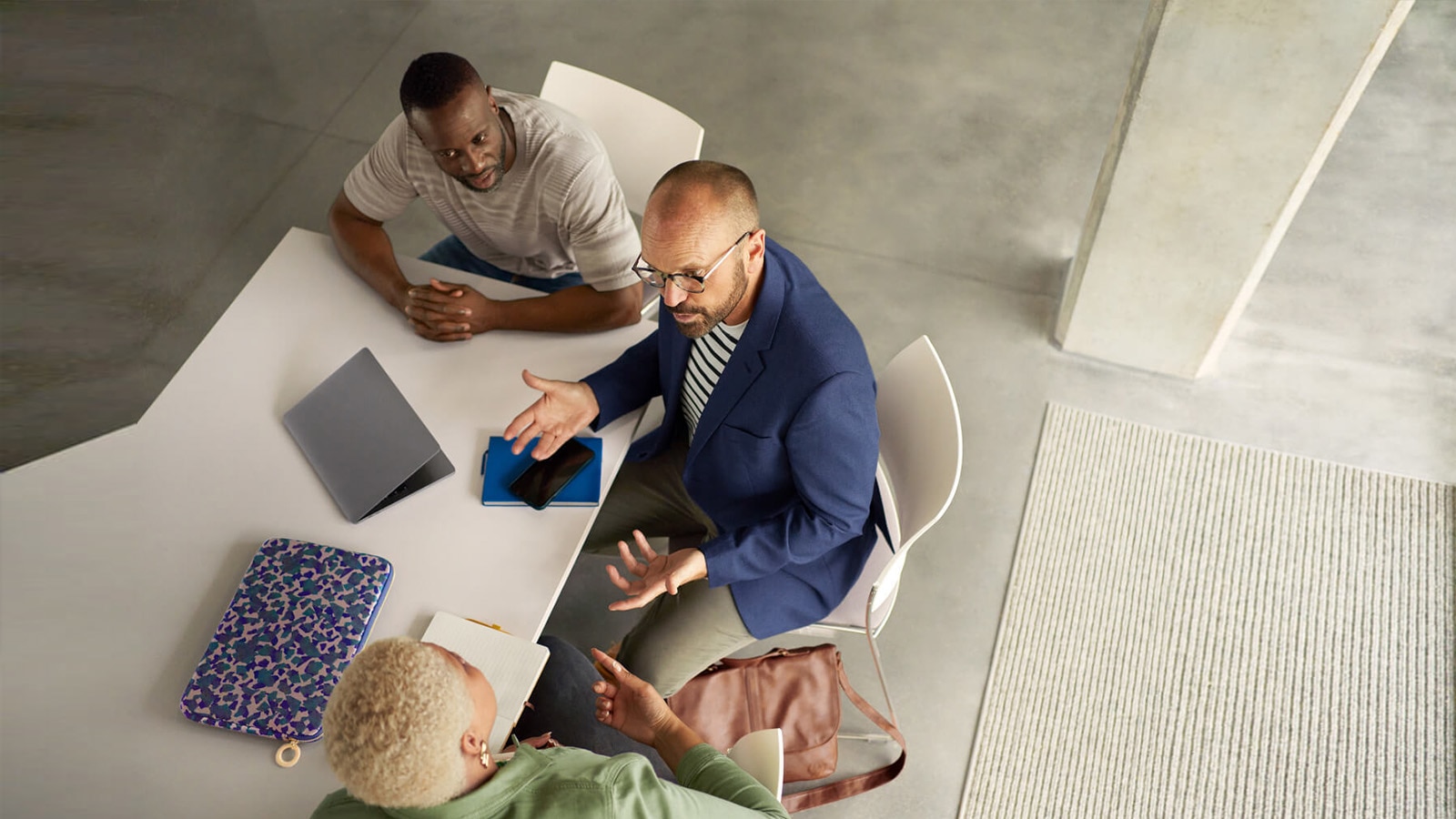  Menschen sitzen an einem Tisch, besprechen betriebliche Sicherheit