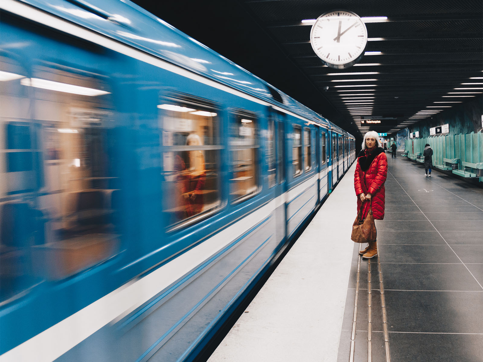 Woman standing by train at railroad station platform in Stockholm.